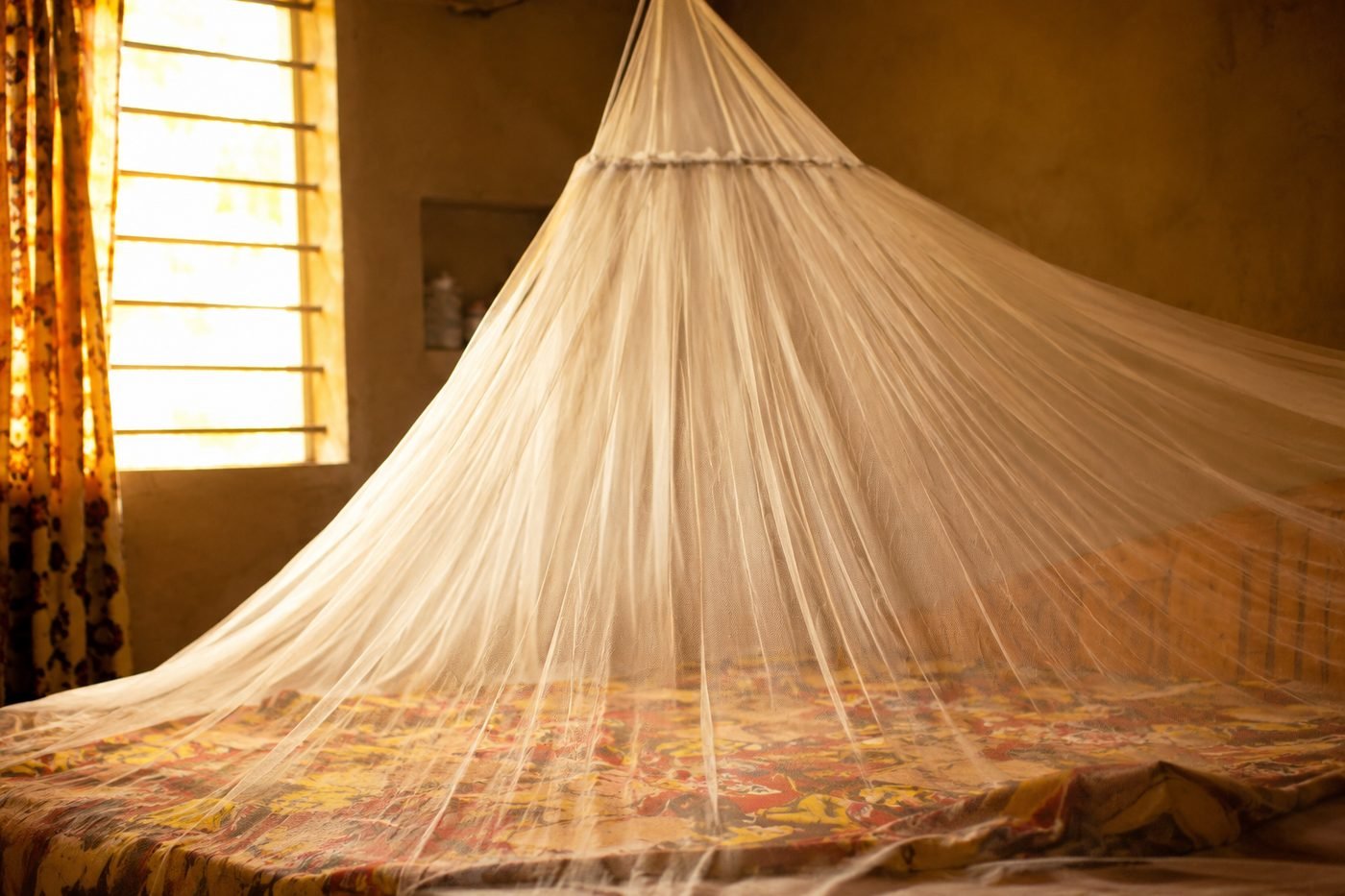 Moustiquaire imprégnée suspendue au-dessus d'un lit, geste de prévention du paludisme au Bénin